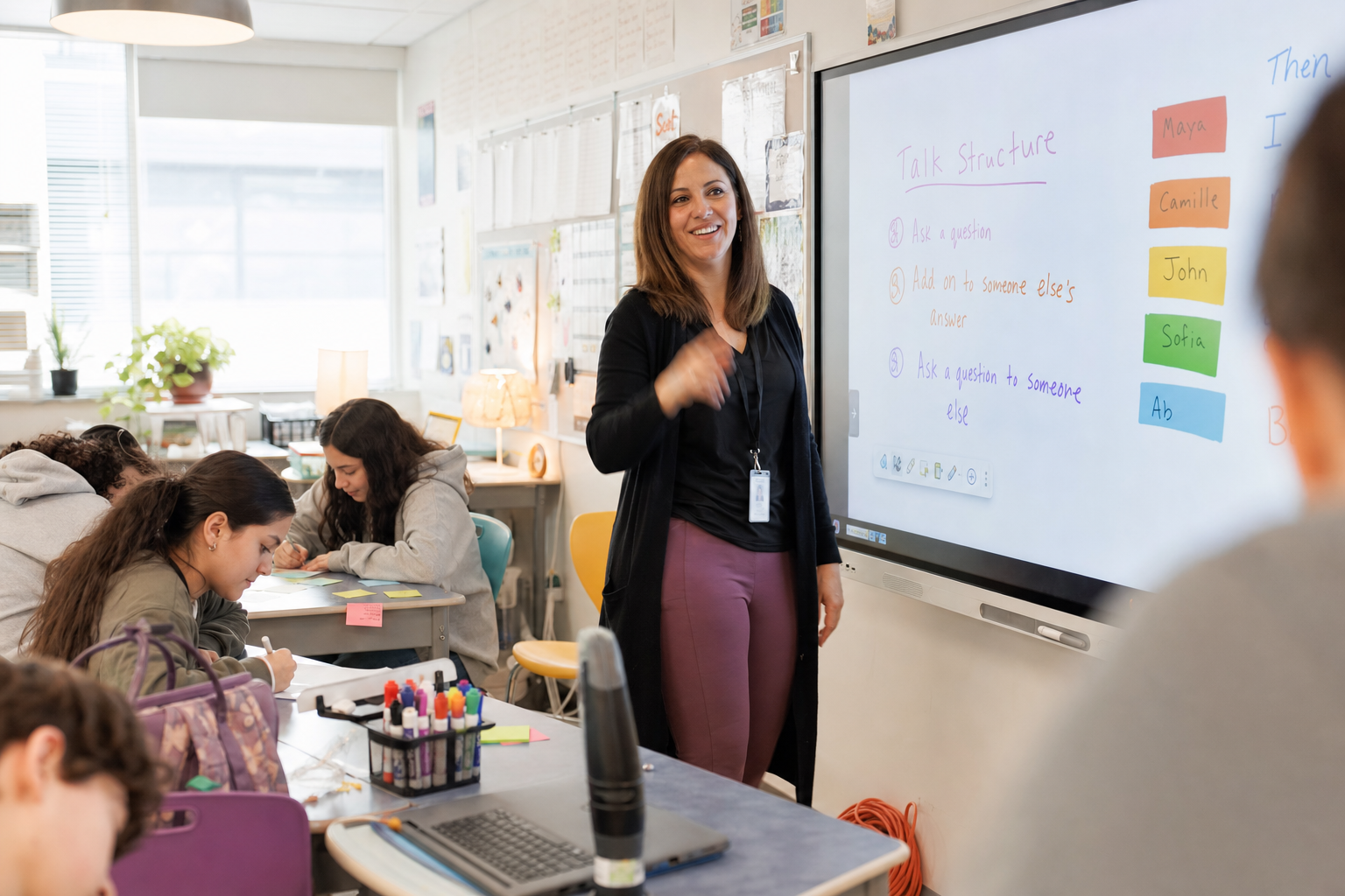 Docent staat voor een digitaal schoolbord terwijl leerlingen in de klas aan opdrachten werken.
